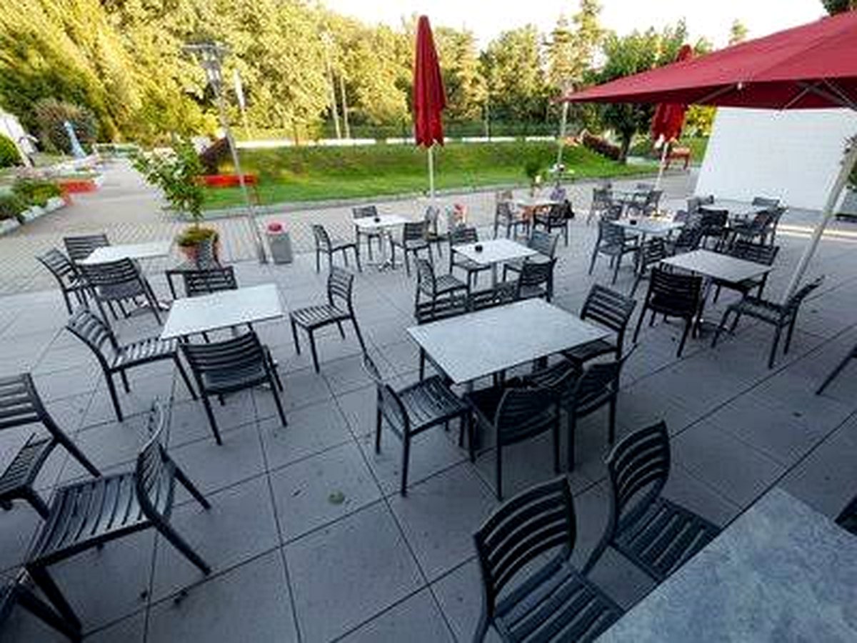 Terrasse mit Tischen, Stühlen und Sonnenschirmen vor dem Clubbad