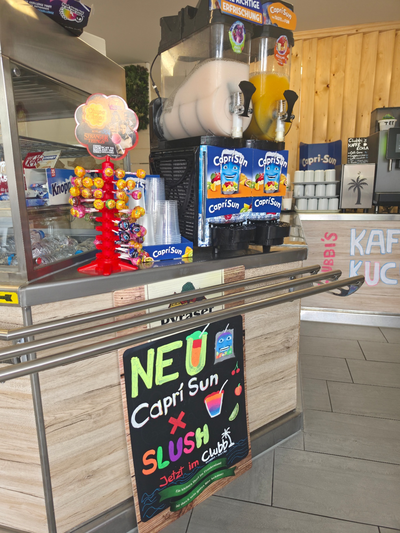 Slush-Maschine mit Capri-Sun und Chupa-Chups-Lollis an der Theke